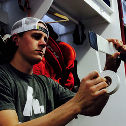 Player taping stick in locker room stall
