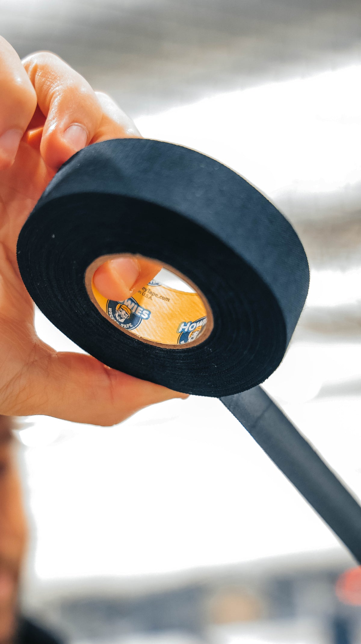 Person holding a roll of black tape with a blurred background