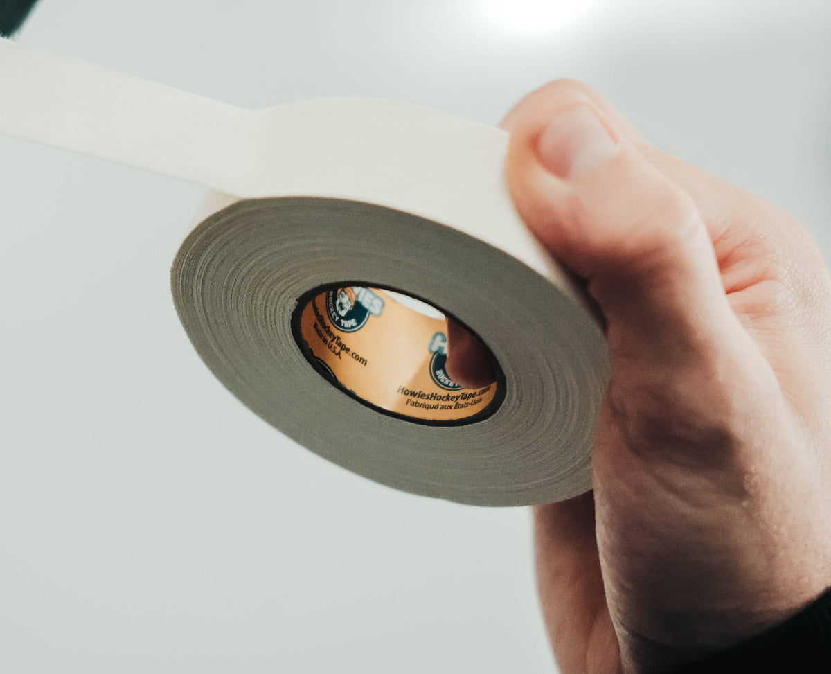 Hand holding a roll of white tape with a blurred background