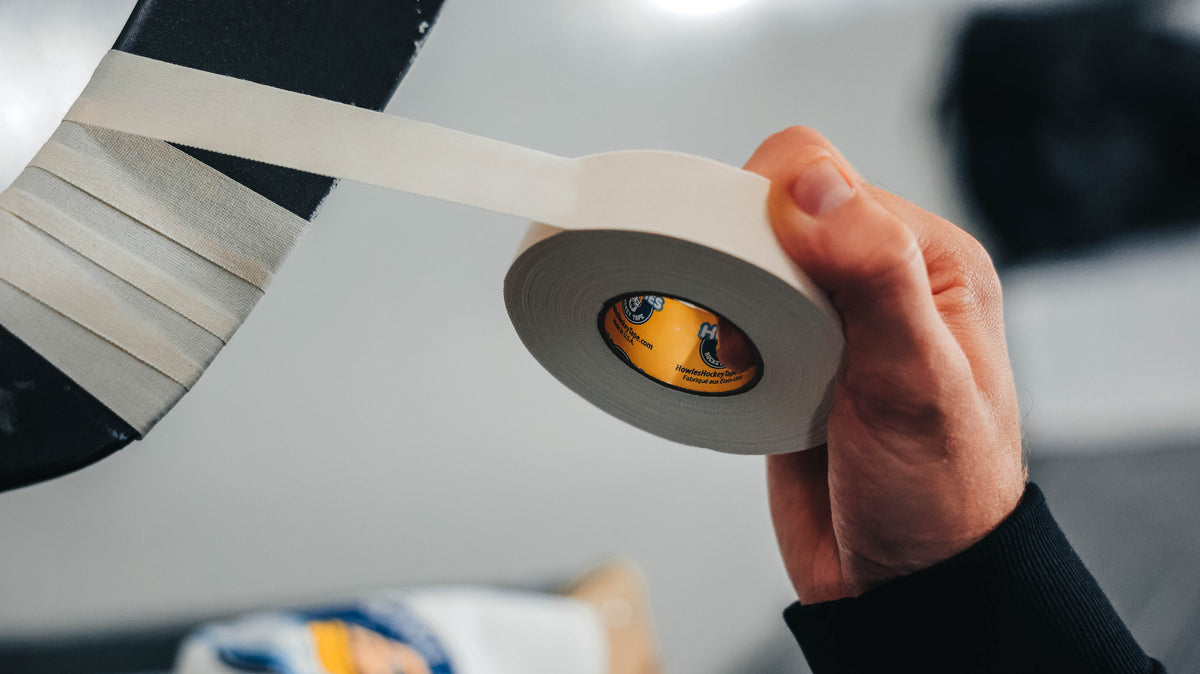 Hand holding a roll of white tape with a blurred background