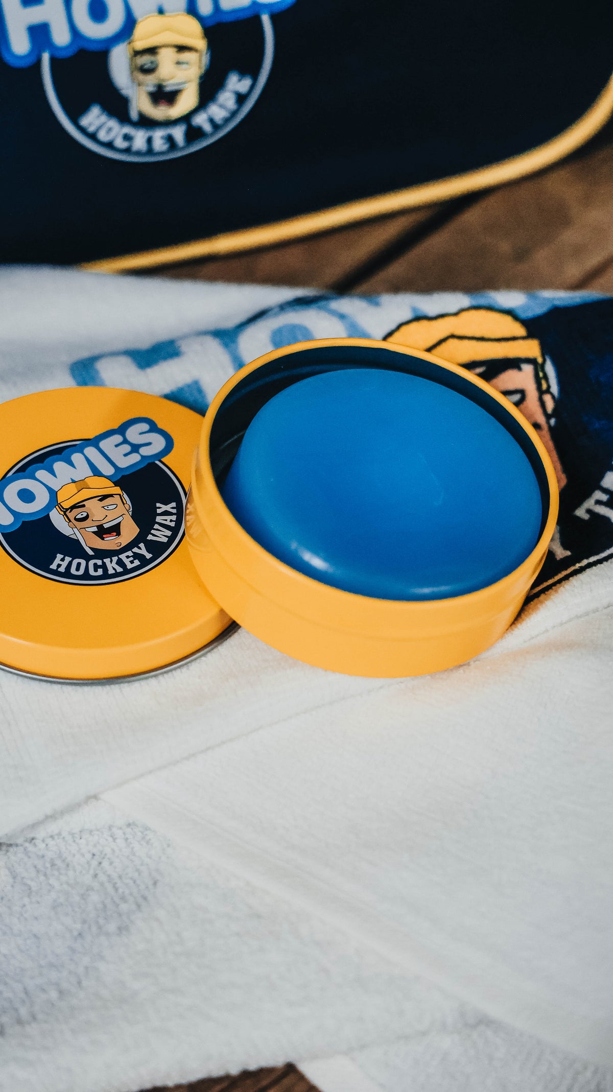 howies hockey wax sitting on a howies bench white towel with a blue howies accessory bag in the back 