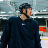 Person wearing a helmet and dark blue jersey on an indoor ice rink