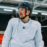 Person wearing a white jersey and protective gear in an indoor setting