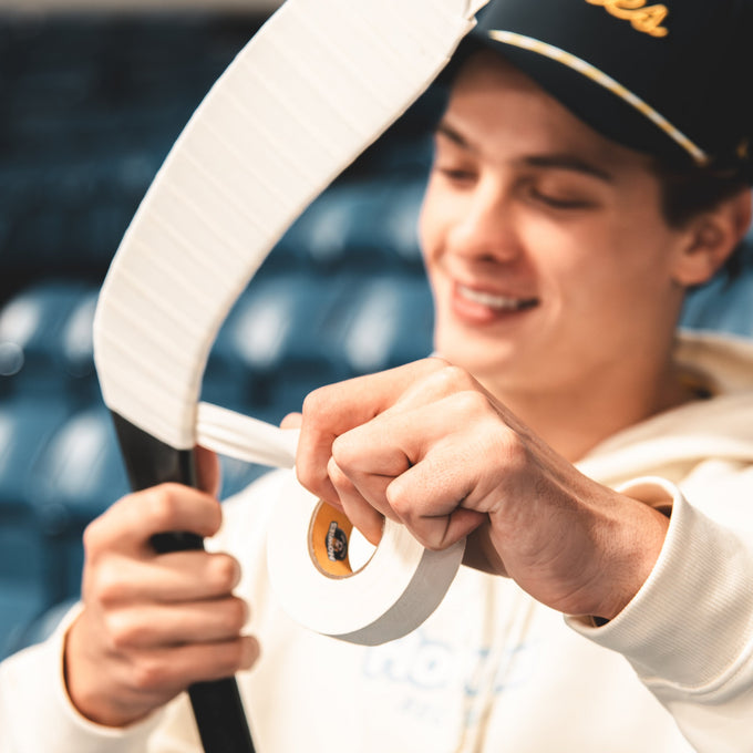 Person holding a hockey stick with a blurred indoor background