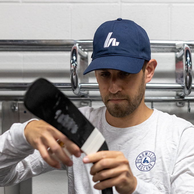guy taping his stick in a navy blue hat 