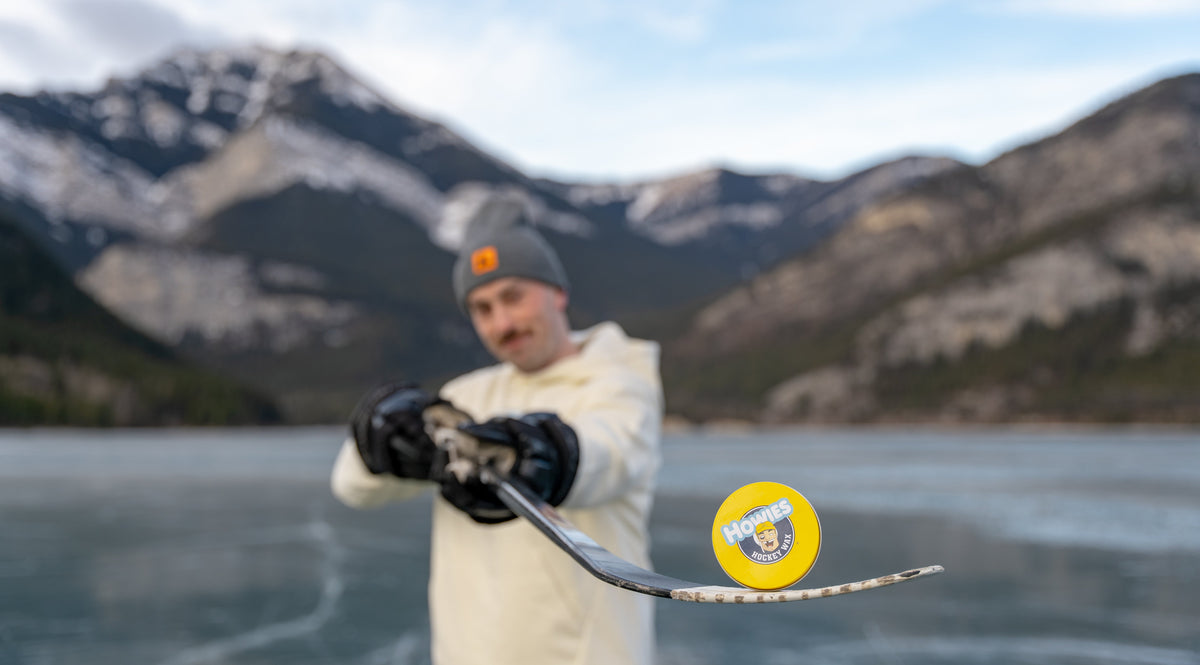 Person holding a hockey stick with a mountain and lake background