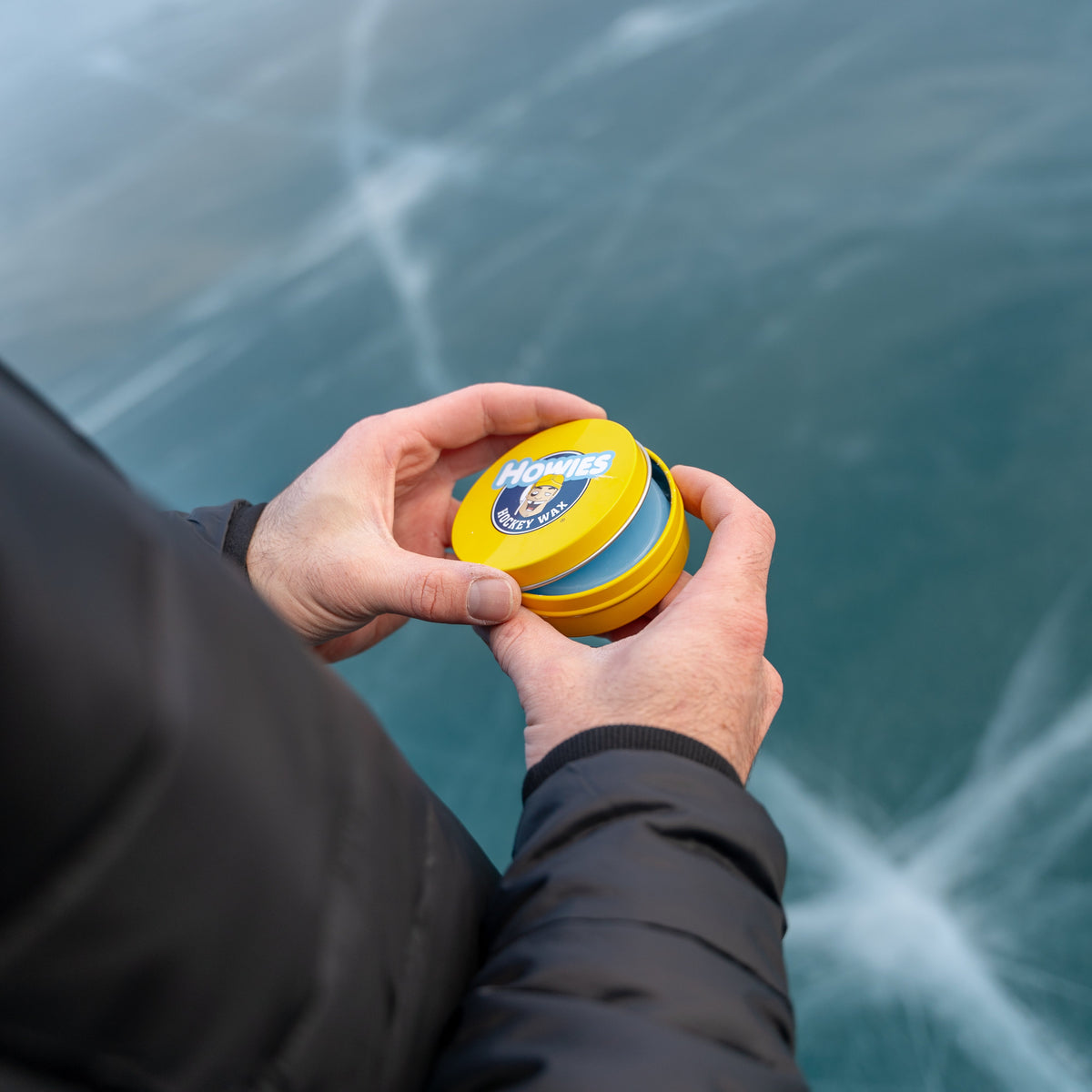 person opening a tin of howies hockey wax 