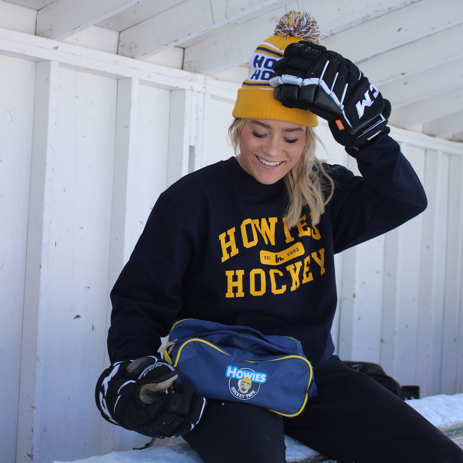 Person wearing a black sweatshirt with 'Howie Hockey' text, standing on a white wooden floor.
