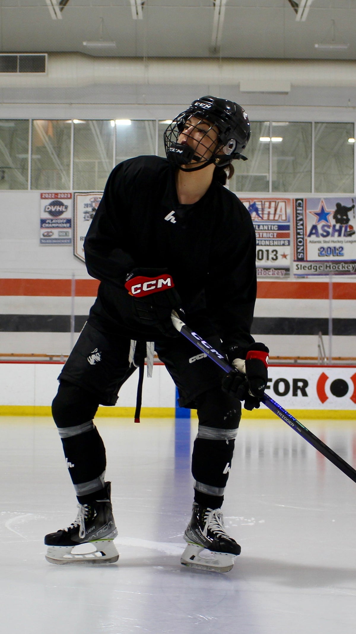 person on the ice in a hockey rink wearing a black howies jersey and black howies pro style socks 