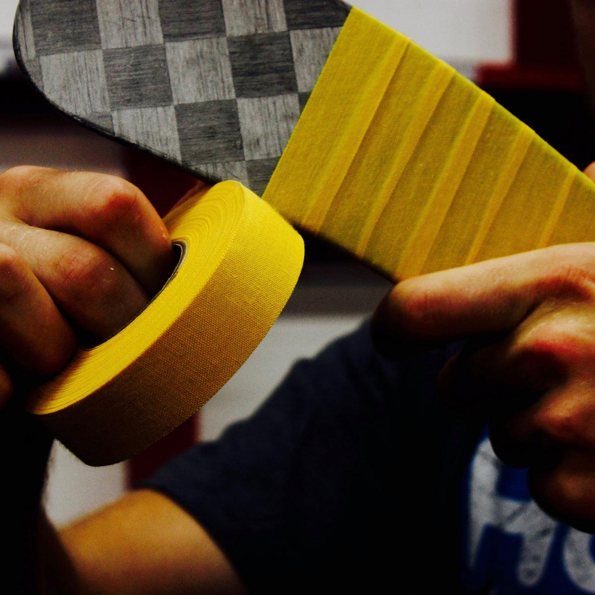 person taping a hockey stick with yellow cloth tape