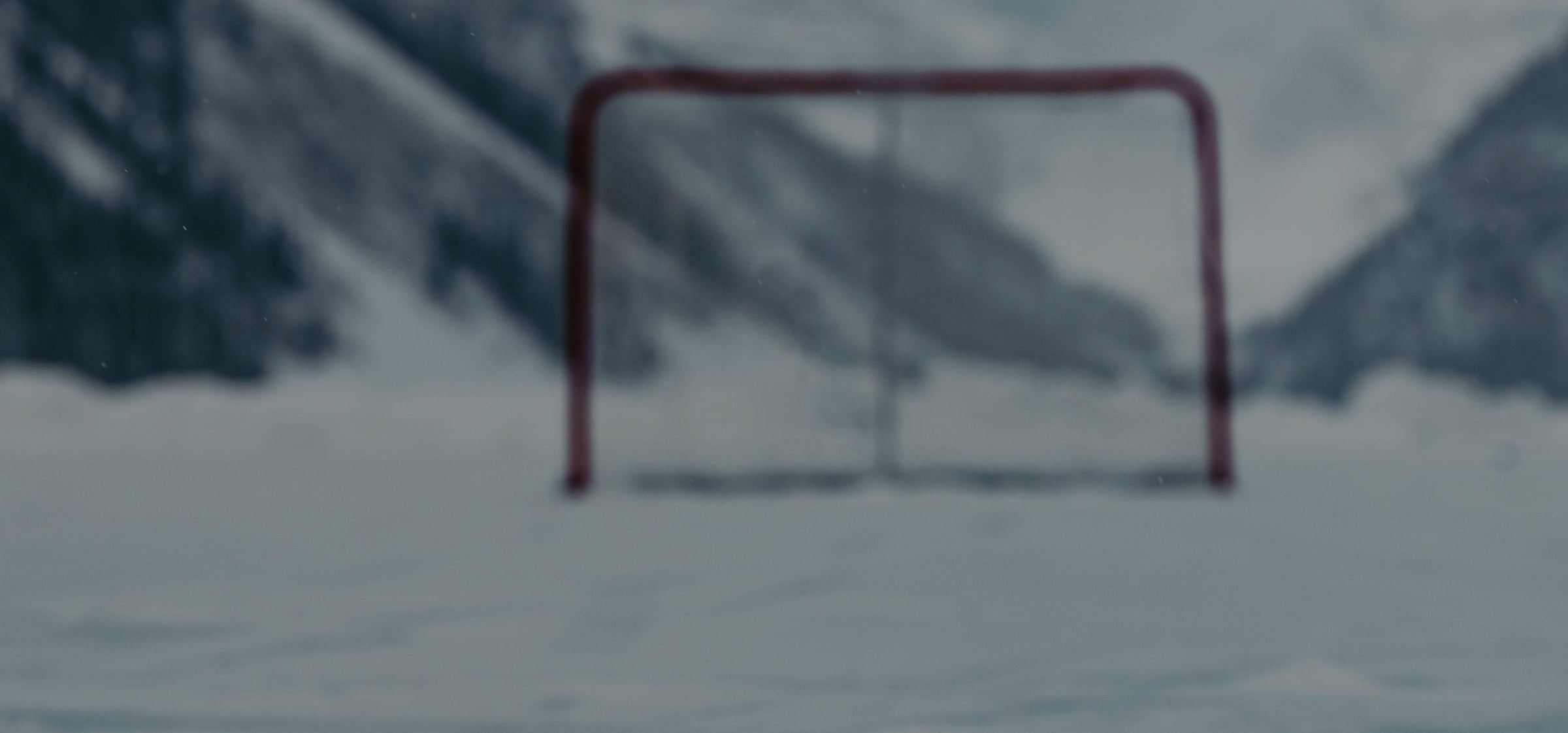 Hockey goal on a snowy pond with mountains in the background