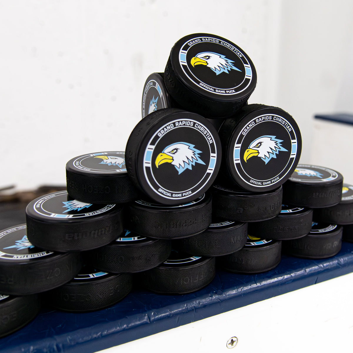 Stack of hockey pucks with a logo on a blue surface