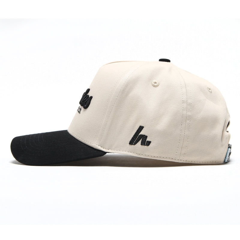 Side profile of the Clean Sheet Lid showing the cream crown, black brim and embroidered Howies "h" side logo