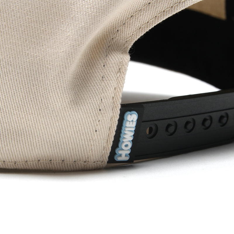 Back of the Clean Sheet Lid showing the black snapback strap with a woven blue and white Howies tag