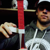 Person holding a red hockey tape with a branded hoodie in the background
